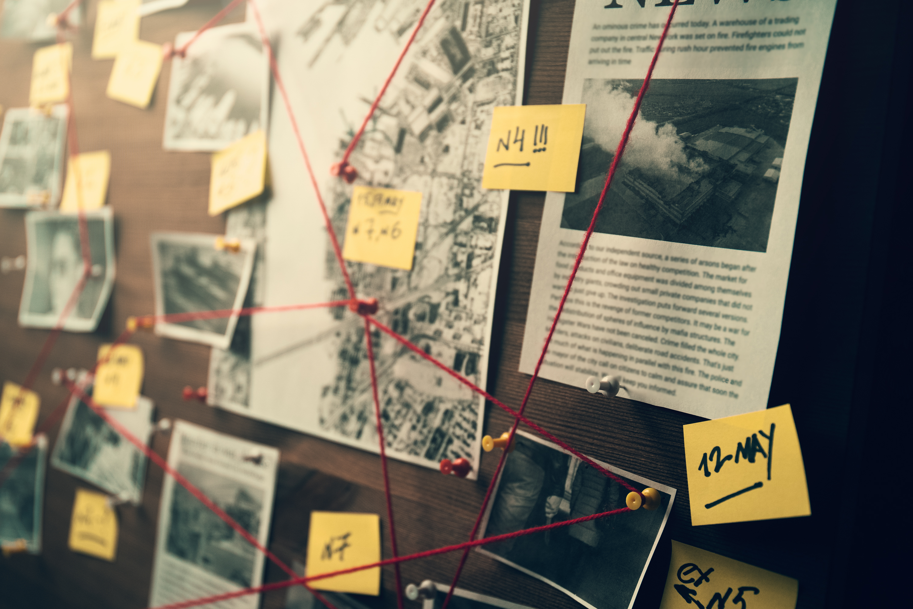 detective board with photos of suspected criminals crime scenes and evidence with red threads 1169378328 3001x2001